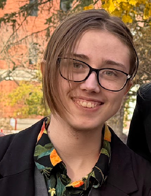 Photo of Jordan Felknor-Wildman, outdoors, smiling at the camera.